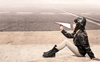 Girl holding paper airplane dreaming big about being a pilot. Parenting means teaching a child like this to dream big..